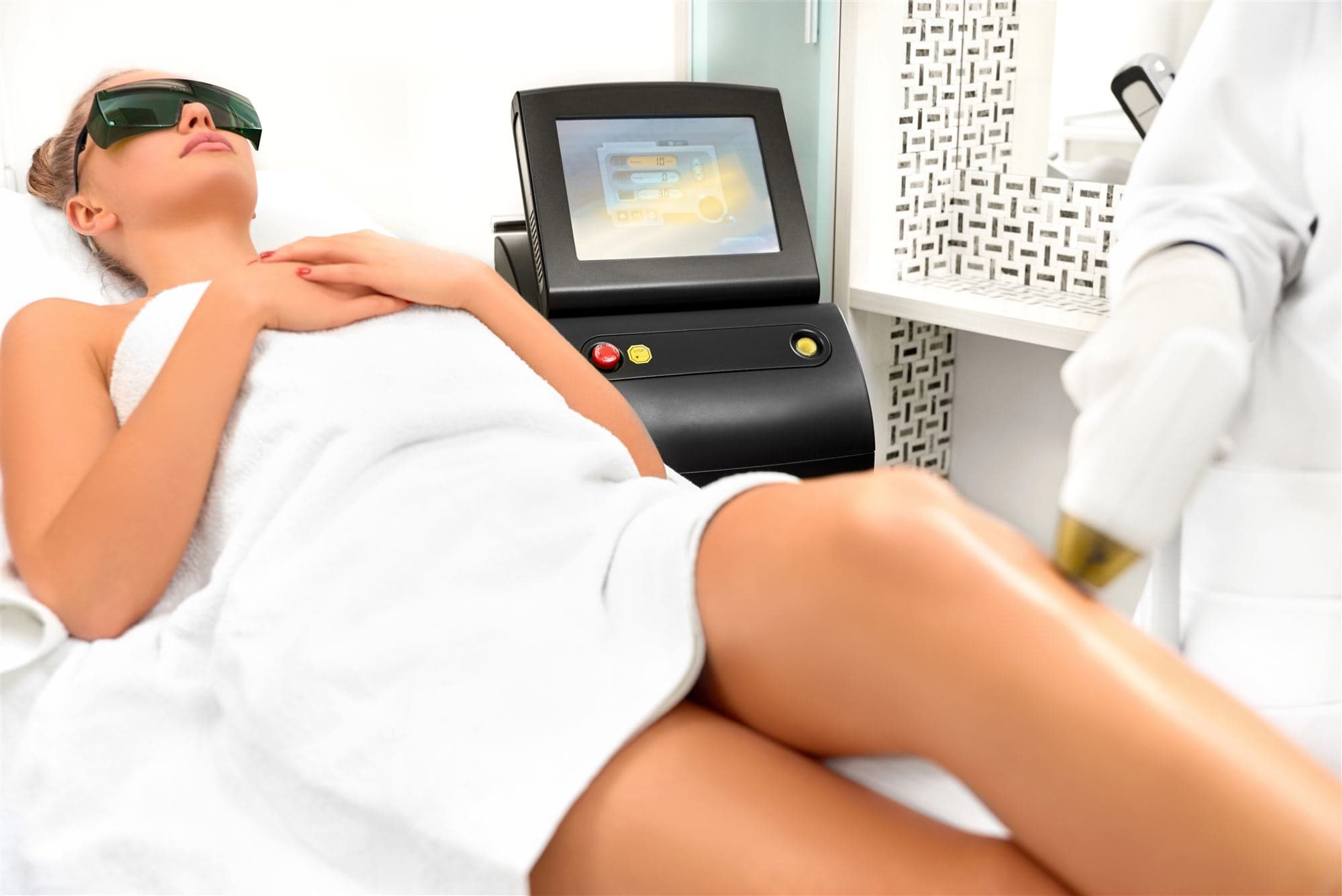 Laser hair removal being carried out on a client’s legs in the treatment room